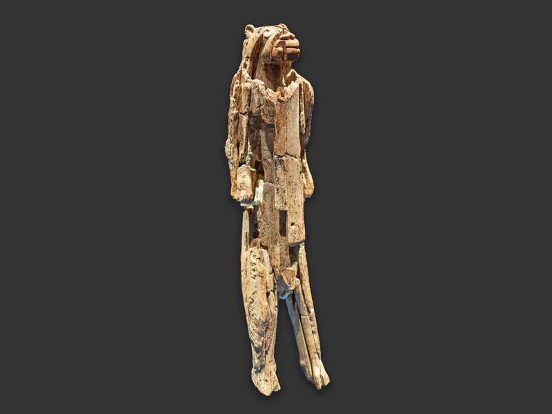 An ivory figurine with a lion head and a human body, standing on a dark background